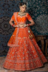 Beautiful woman in vibrant orange lehenga adorned with traditional jewelry.