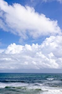 Calm ocean waves beneath a vast, cloudy blue sky. Perfect for relaxation themes.