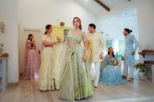 A group of adults in vibrant traditional Indian attire gathered indoors in a well-lit room.