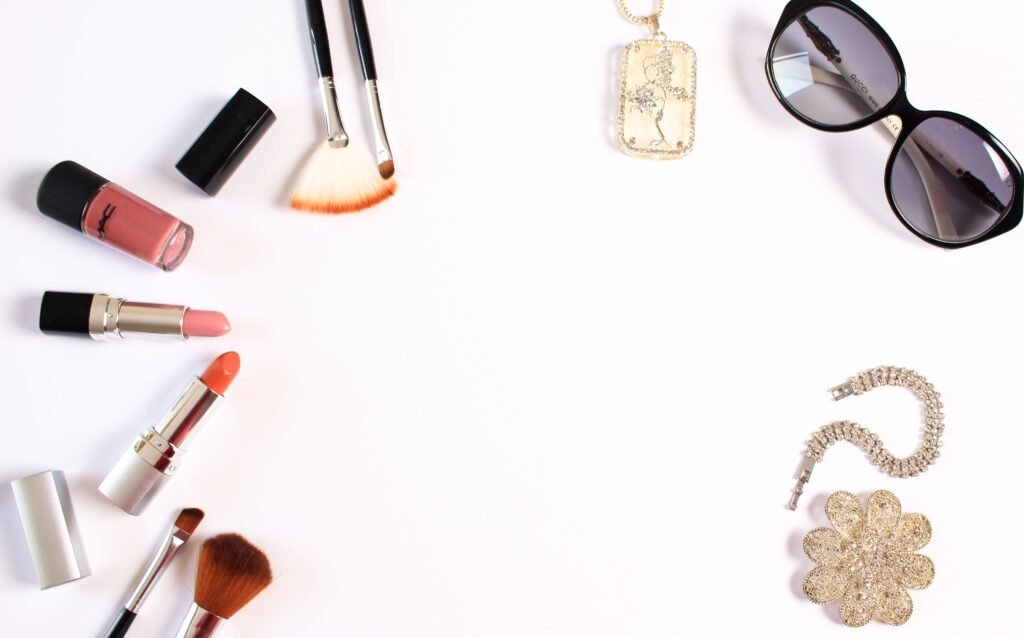 Stylish flat lay of makeup brushes, lipsticks, and glam accessories on a white background.