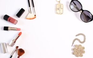 Stylish flat lay of makeup brushes, lipsticks, and glam accessories on a white background.